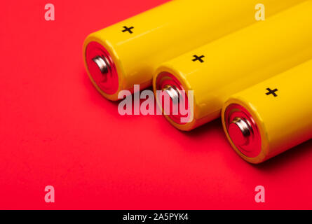 Close up shot of yellow AA alkaline or rechargeable NiMH batteries on red background, shallow focus Stock Photo