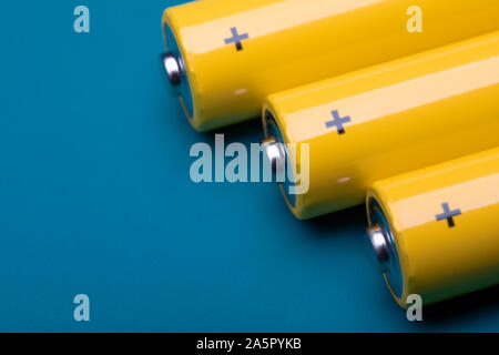 Close up shot of yellow AA alkaline or rechargeable NiMH batteries on blue background, shallow focus Stock Photo
