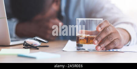 Drunk businessman sleeping at workplace with whiskey glass in hand Stock Photo