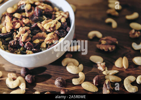 white bowl with mixed nuts on rustic wooden table, healthy food and snack concept Stock Photo