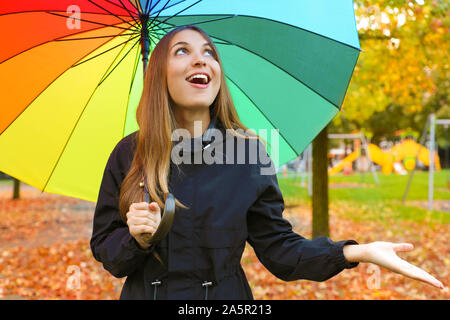 Laughing young woman with colorful umbrella checking for rain. Stock Photo