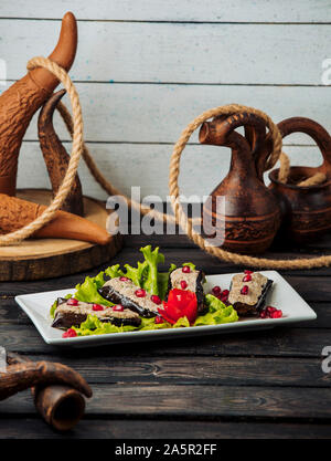 fried aubergine halves topped with chicken and walnut mix garnished with pomegranate Stock Photo