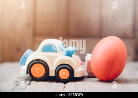 Easter egg and toy car on wooden background, happy easter day concept Stock Photo
