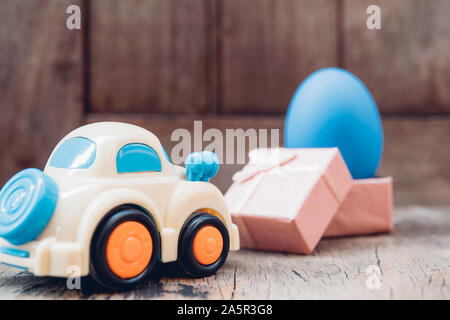 Easter egg and toy car on wooden background, happy easter day concept Stock Photo