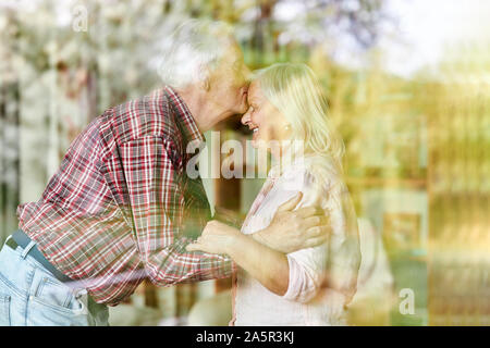 Senior kissing his wife's forehead tenderly as a sign of love