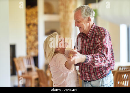 Couple of seniors dancing happily together in the living room or nursing home Stock Photo