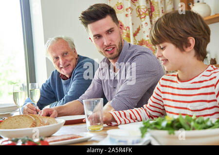 Family with grandfather and grandson having lunch together at the dining table Stock Photo