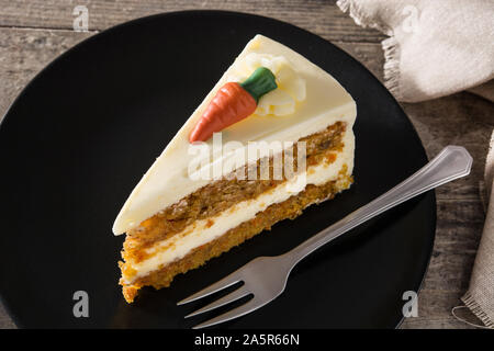 Sweet carrot cake slice on a plate on wooden table.