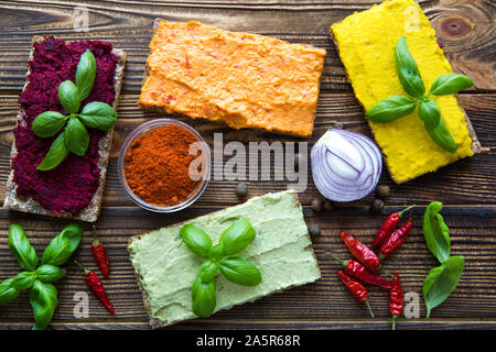 Assortment of bruschettas with hummus on brown table. Avocado, curry, paprika and beetroot taste with fresh basil and onion. Close up. Stock Photo