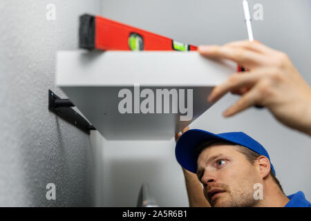 handyman installing shelf on the wall at home Stock Photo