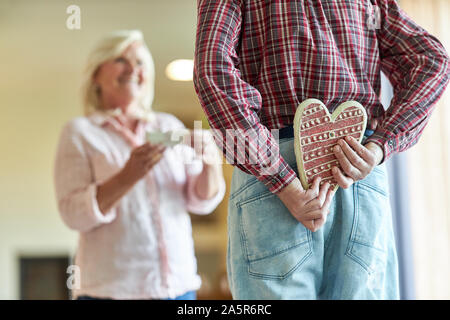 Senior hides a gingerbread heart as a gift surprise for his wife Stock Photo