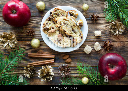 Traditional Christmas cake on brown table, golden cones, fir tree branches decorations. Top view. Stock Photo