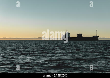 Large cargo ship cruising against late afternoon sky in La Paz, BCS Stock Photo