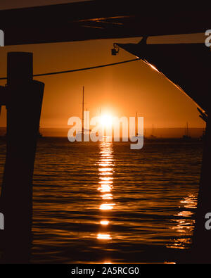 Sun descends into ocean at La Paz BCS Marina. Sunset in between boats docked at the marina. Stock Photo