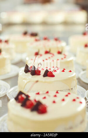Red cherry on white cake on a table with cakes Stock Photo