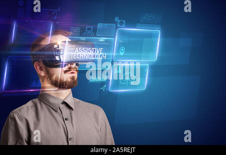 Businessman looking through Virtual Reality glasses with ASSISTIVE TECHNOLOGY inscription, new technology concept Stock Photo