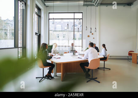 Group of diverse businesspeople sitting together around a boardroom table in an office discussing work Stock Photo