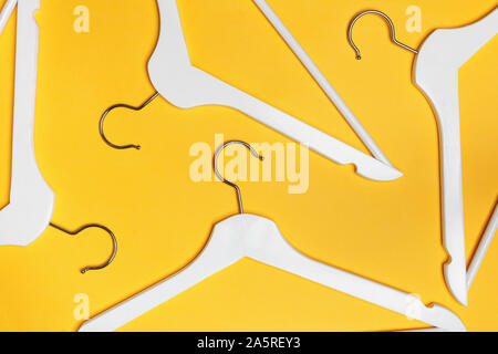 White hangers on a yellow background. Flat lay. Top view. The concept of shopping, sales, storage. Stock Photo