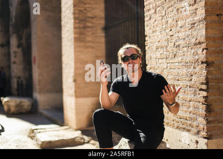 Young male tourist using smartphone inside Colosseum in Rome, Italy. Stock Photo