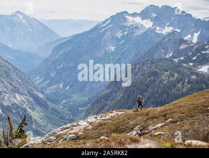 A male hiker walks on a trail with a view in the Cascades, Washington Stock Photo