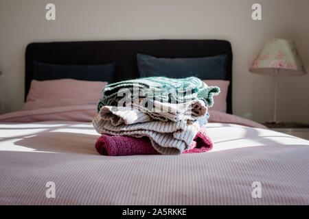 neatly folded winter fair isle sweaters on a bed in a bedroom at home Stock Photo