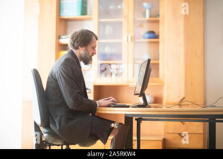 older man with prosthetic leg working at home Stock Photo