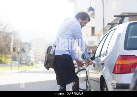 older man with prosthetic leg opening car Stock Photo