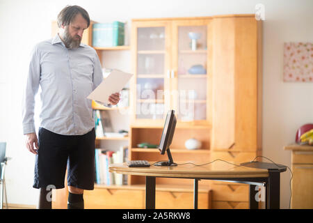 older man with prosthetic leg working at home with laptop Stock Photo
