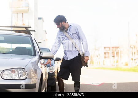 older man with prosthetic leg opening car Stock Photo