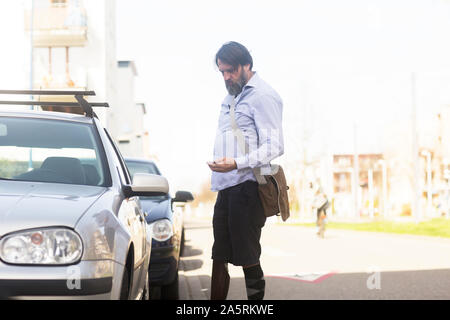 older man with prosthetic leg opening car Stock Photo