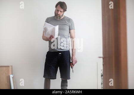 older man with prosthetic leg  working at home Stock Photo