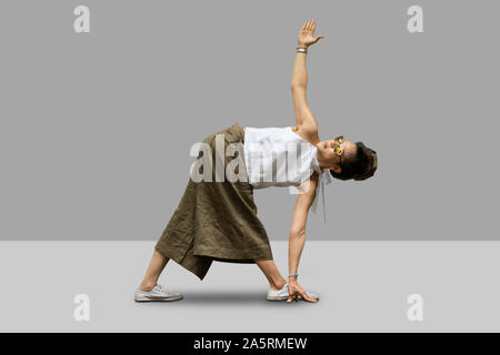yoga female  standing in Utthita Trikonasana, Extended Triangle Pose on grey background. Stock Photo