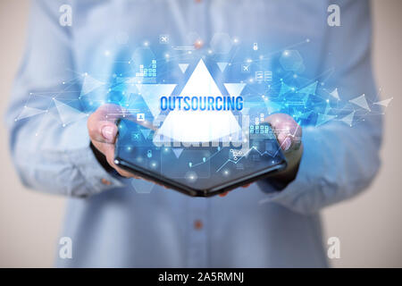 Businessman holding a foldable smartphone with OUTSOURCING inscription, business concept Stock Photo