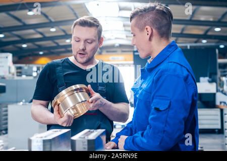 Master discussing a workpiece with his apprentice or trainee Stock Photo