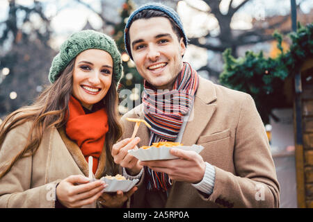 Man and woman eating snacks on a Christmas Market Stock Photo