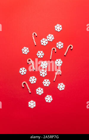 Winter xmas holiday theme. Christmas pattern with festive white snowflakes and red candy cane. Flat lay, top view, copy space Stock Photo