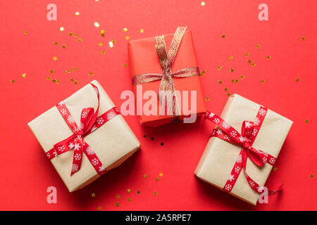 Modern in craft multicolor paper surprise boxes with gold shiny bow ribbons on a red background. Birthday banner, photo for article, birthday poster o Stock Photo
