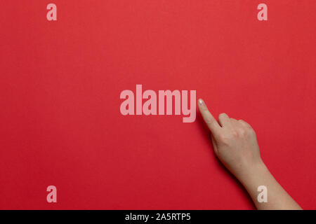 Woman hand show hand with forefinger up for point something isolated on red background. Flat lay style composition, top view. Stock Photo