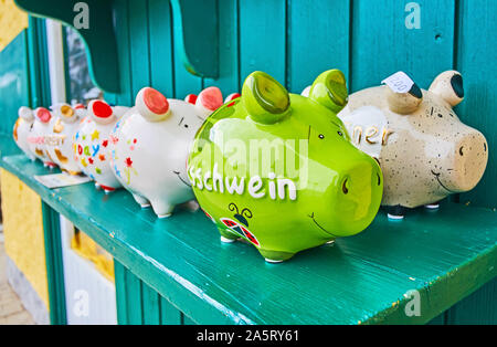 HALLSTATT, AUSTRIA - FEBRUARY 21, 2019: The colorful piggy banks wait for their owners in souvenir store of the town, on February 21 in Hallstatt Stock Photo