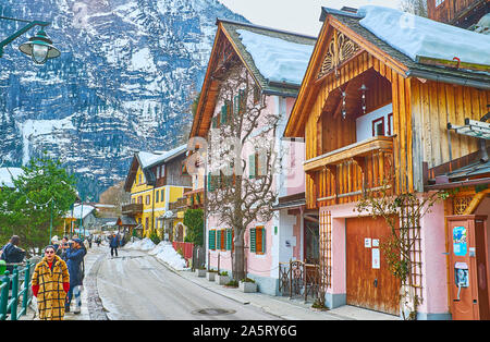 HALLSTATT, AUSTRIA - FEBRUARY 21, 2019: The lakeside neighborhood with old wooden houses and many souvenir stores is always full of tourists, walking Stock Photo