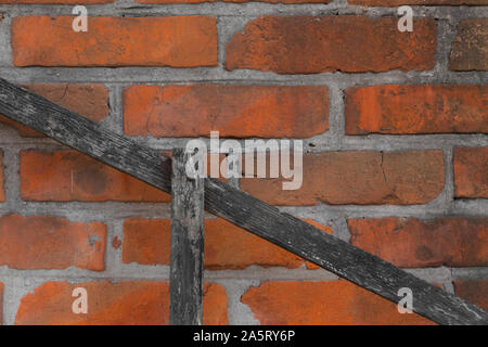 old red brick wall with Diagonal wooden board - background texture. Stock Photo