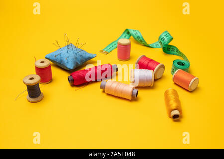 Composition with threads and sewing accessories on a yellow background. Top view, flat lay. Copy space for text. Stock Photo