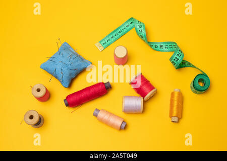 Composition with threads and sewing accessories on a yellow background. Top view, flat lay. Copy space for text. Stock Photo