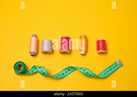 Composition with threads and sewing accessories on a yellow background. Top view, flat lay. Copy space for text. Stock Photo