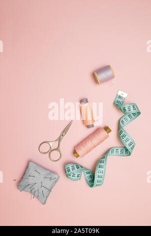 Top view of sewing machine with accessories for sewing, scissors and a measuring tape on pink background with place for text. Vertical position Stock Photo