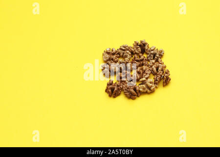Heap of walnuts on a yellow background. Calorie Nuts and Healthy Eating Concept Stock Photo