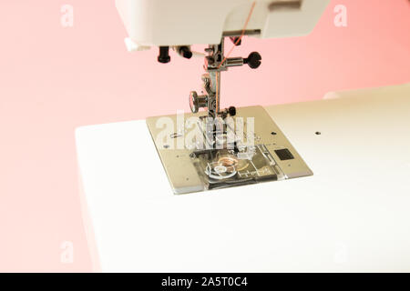 Close-up of a sewing machine on a pink background. Preparation for the production process. Can be used for article, web banner or poster. Stock Photo