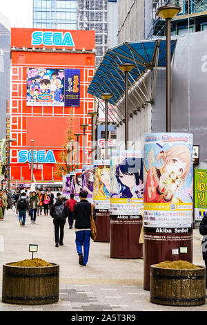 Tokyo, Akihabara, electric town. View along a row of round stands with Akiba smile campaign posters on, in front of the iconic red Sega building. Stock Photo