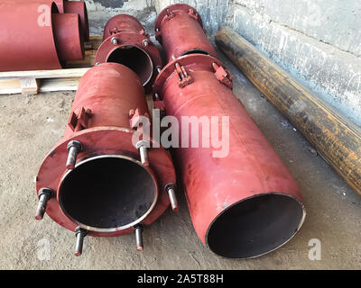 Red gland expansion joints for heating main on concrete floor. Heat and power concept. Stock Photo