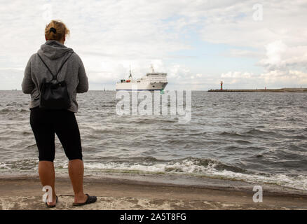 merchant ship entering the Baltic port in Poland,woman on the sea shore Stock Photo